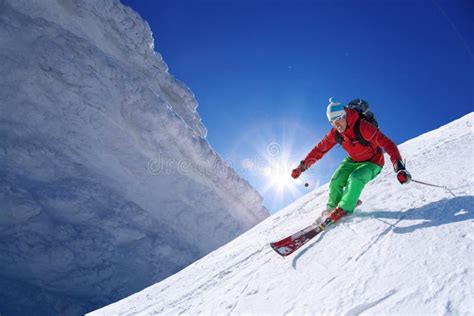 Skier Skiing Downhill In High Mountains Against Sunset Stock Photo