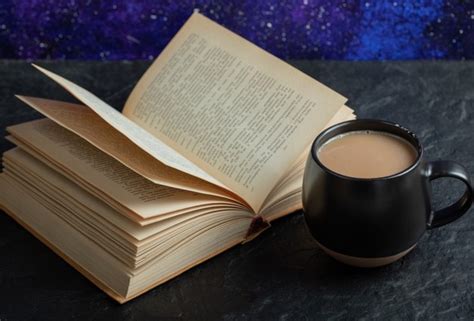 Eine tasse kaffee mit buch auf einer dunklen oberfläche. | Kostenlose Foto