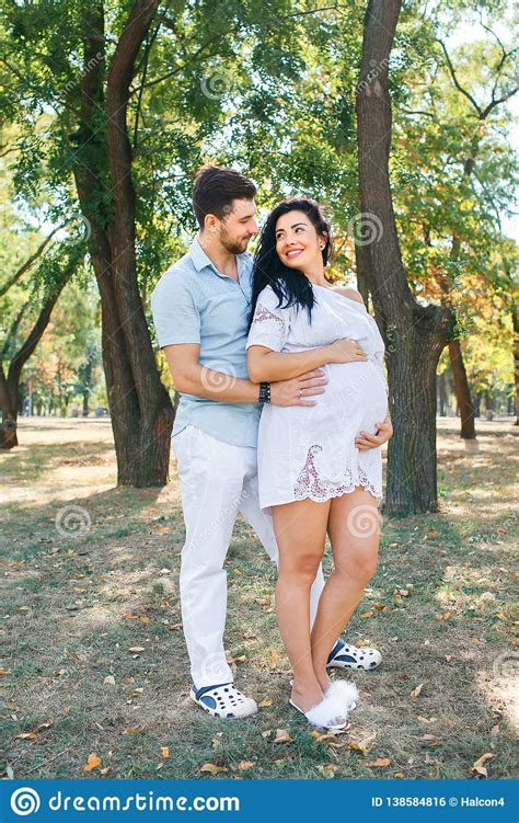 Pregnant Girl Walks In The Park With Her Husband Hugging And Kissing Enjoying The Beautiful