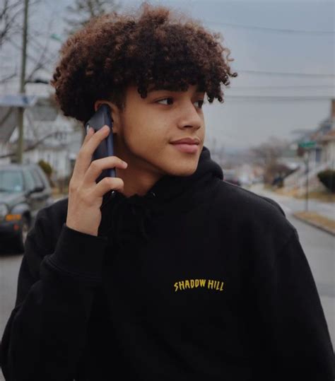 A Young Man Talking On A Cell Phone While Wearing A Black Hoodie With