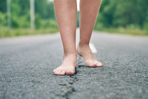 Bare Feet Of A Young Girl Walking Along The Asphalt Road Stock Image
