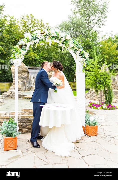 First Kiss Of Newly Married Couple Under Wedding Arch Stock Photo Alamy