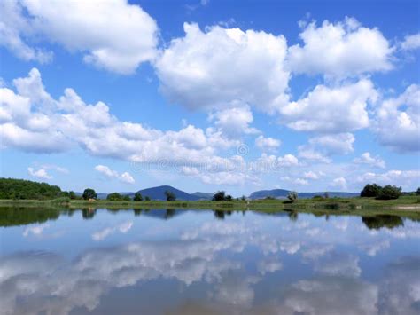 Reflection Of The Cloudy Blue Sky In The Lake Surface Stock Photo