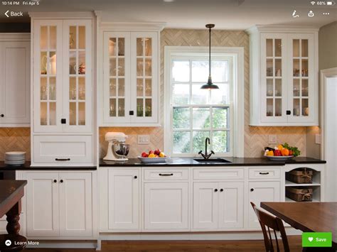 A Kitchen With White Cabinets And Black Counter Tops Along With A