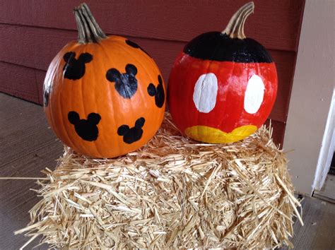 Two Pumpkins Painted To Look Like Mickey And Minnie Mouse Heads On Hay