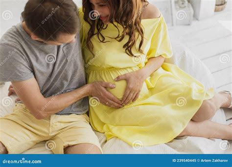 Cropped Image Of Beautiful Pregnant Woman And Her Handsome Husband Hugging The Tummy Stock