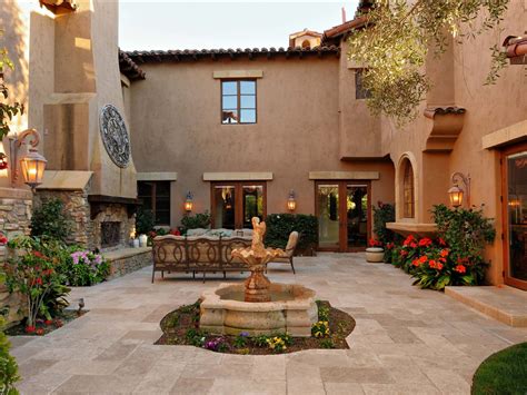 An Outdoor Patio With A Fountain Surrounded By Flowers