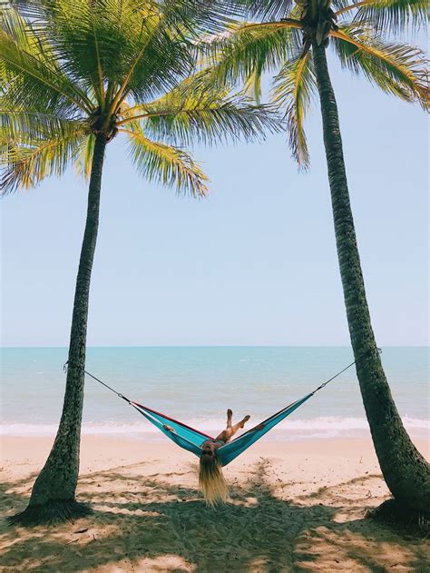 Swinging In A Hammock On The Beach Between Two Palm Trees In Australia