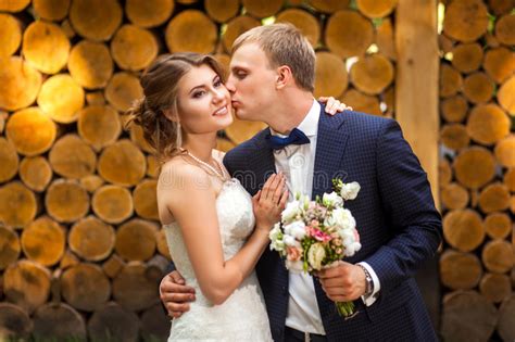 Groom Kissing Bride Near Wooden Logs Stock Photo Image Of Standing
