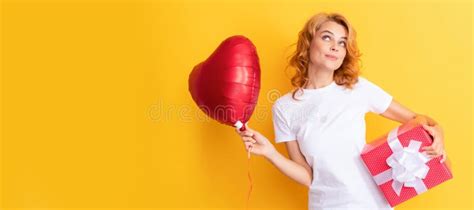 smiling pondering redhead woman with red heart balloon and t box be my valentine stock image