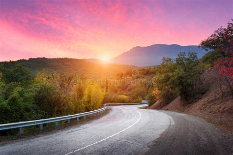 Mountain Road Passing Through The Forest With Dramatic Colorful Sky And