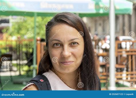 portrait of a 40 year old brunette woman on a neutral urban background smiling mysteriously