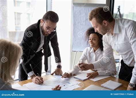 Motivated Diverse Employees Brainstorming Discussing Paperwork At