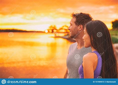 Couple Relaxing On Beach Watching Sunset Glow Over Ocean In Caribbean Background Asian Girl