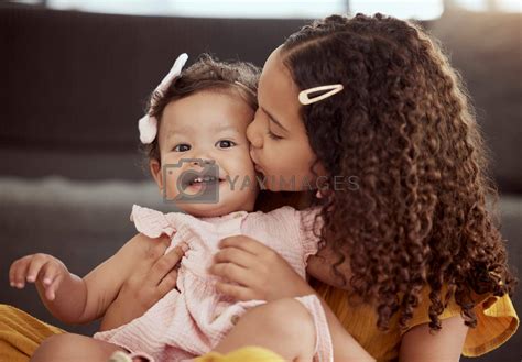Adorable Little Mixed Race Child Kissing Baby Sister On The Cheek At