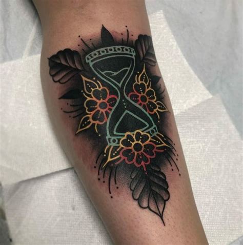 A Tattoo With An Hourglass And Flowers On It
