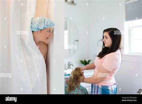 A Mom Is In The Shower As Her Daughters Get Ready In The Bathroom Stock