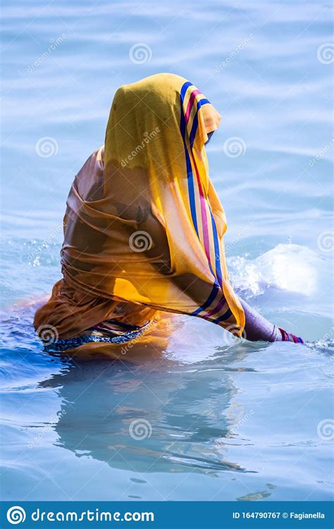 Life On The Ganges Woman In A Bright Yellow Or Orange Sari Bathing In