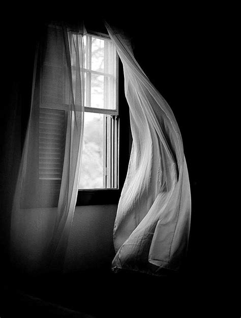 An Open Window With Sheer Curtains In The Dark