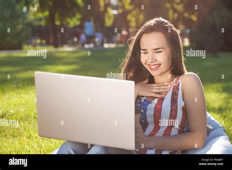 Pretty Young Woman Sitting On Bean Bag Use Laptop While Resting On