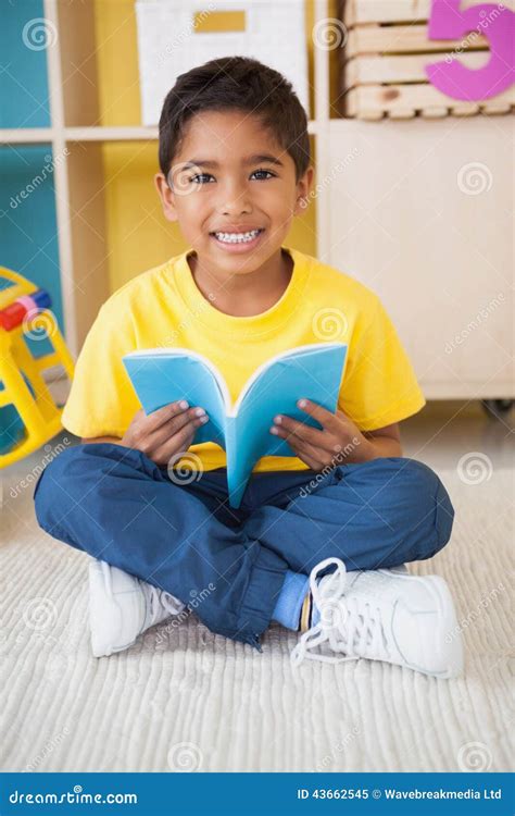 Cute Little Boy Sitting On Floor Reading In Classroom Stock Image