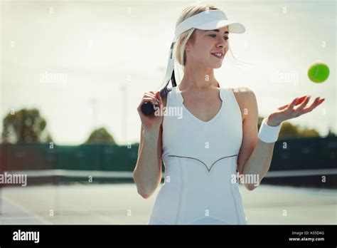 Smiling Young Female Tennis Player Holding Tennis Racket And Tennis