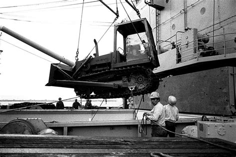 Seabees Load Heavy Equipment Aboard The Amphibious Cargo Ship Uss