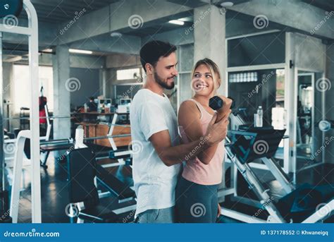 Sporty Couple Exercising Dumbbell Weights Lifting In Fitness Gym