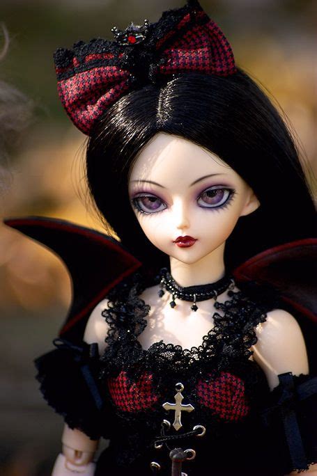 A Close Up Of A Doll With Black Hair Wearing A Red And Black Outfit On