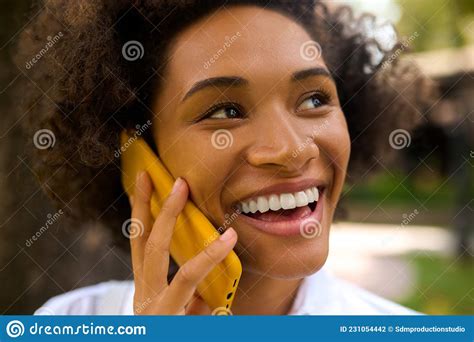 A Curly Haired Girl Talking On The Phone And Looking Pleased Stock