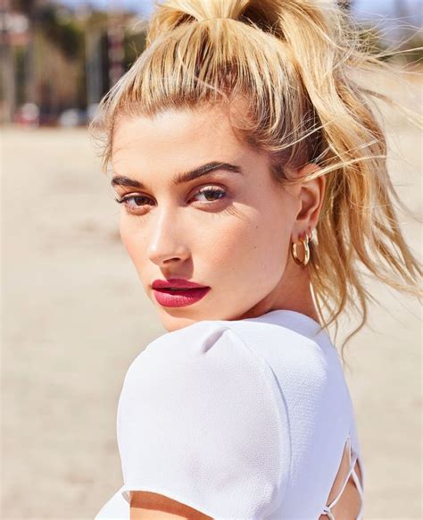 A Woman With Blonde Hair Wearing A White Top And Red Lipstick Posing
