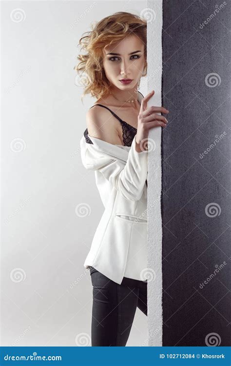 Young Model Posing Near Black Wall Undressing Her White Ja Stock Photo