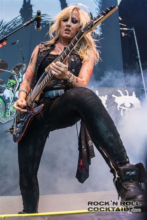 A Woman With Long Blonde Hair Playing Guitar On Stage