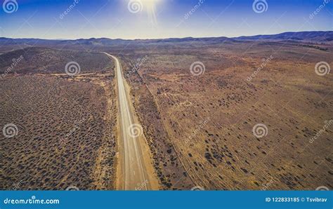 Rural Road Passing Through Dry Land With Scarce Vegetation Stock Image