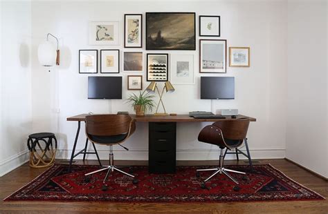 Two Chairs Sitting At A Desk In Front Of Pictures On The Wall