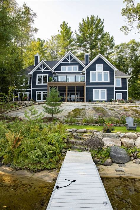 A Dock Sits In Front Of A Large Blue House On The Waters Edge