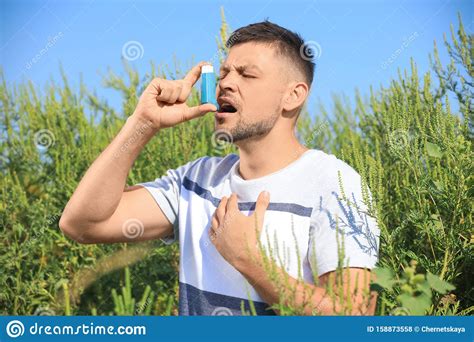 Man With Inhaler Suffering From Ragweed Allergy On Sunny Day Stock