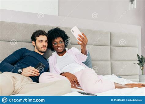 Beautiful Young Loving Couple Lying In Bed And Making Selfie Stock