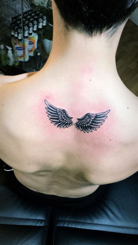 The Back Of A Woman S Neck With An Angel Wing Tattoo On It