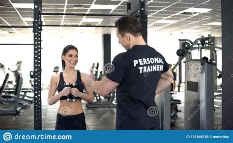 Personal Trainer Showing Thumbs Up To Fit Girl While Exercising