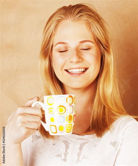 Young Cute Blond Girl Drinking Coffee Close Up On Warm Brown Bac Stock