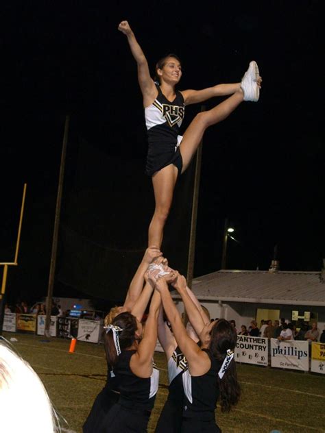 Cheer High School Cheerleader Doing A Heel Stretch At A Football Game