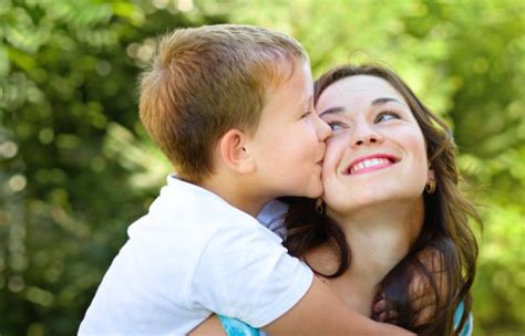 Madre Besando A Su Hijo En La Mejilla Durante El Verano Fotografía De