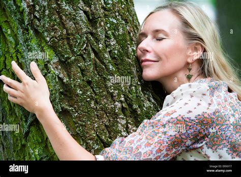 Blond Woman Hugging A Tree In A Park Stock Photo Alamy