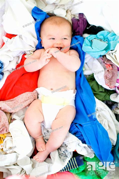 Overhead Portrait Of Baby Girl Lying Amongst Laundry Stock Photo