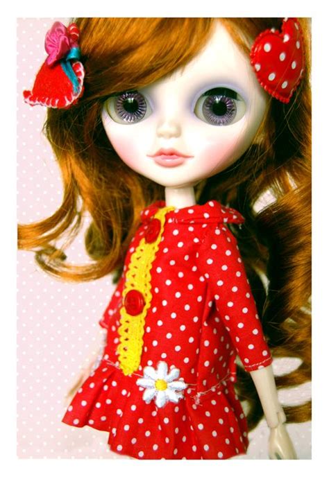 a close up of a doll wearing a red dress with white polka dots on it