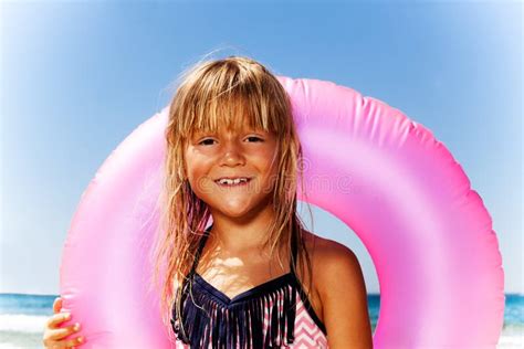 Śliczna Mała Dziewczynka Z Menchiami Pływa Pierścionek Na Plaży Zdjęcie