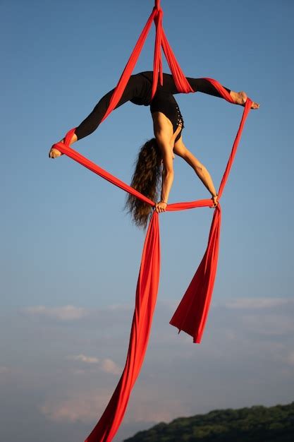 premium photo beautiful and flexible female circus artist dancing with aerial silk on a sky