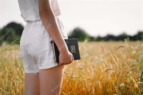 premium photo girl holds bible in her hands reading the holy bible in a field concept for