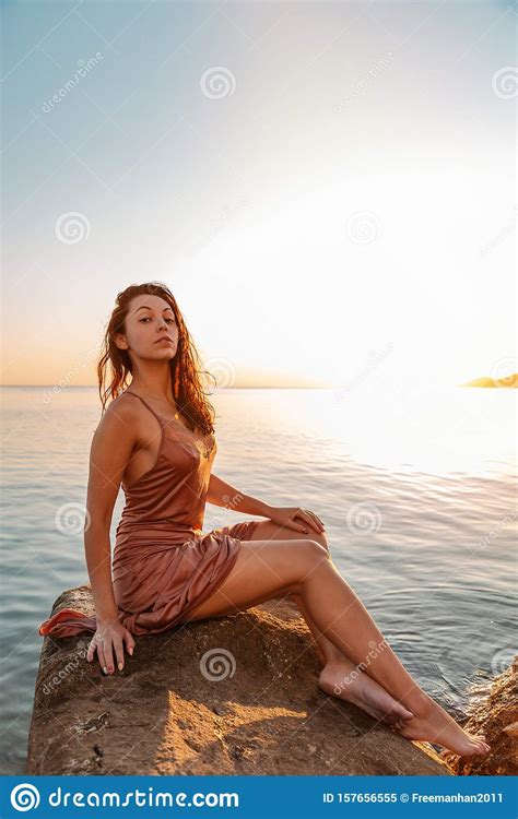 Beautiful Woman In Lingerie Posing On A Coastal Cliff Sea And Sunset
